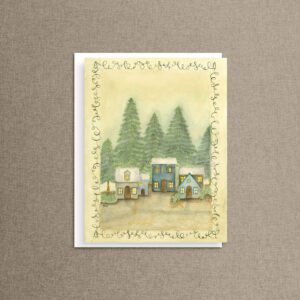 Nestled in the Trees winter village notecard styled with a white envelope on a linen background
