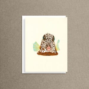 Watercolor trunkfish notecard called Polka Dot Kiss, with a spotted boxfish illustration on a cream card, propped on a taupe linen background.