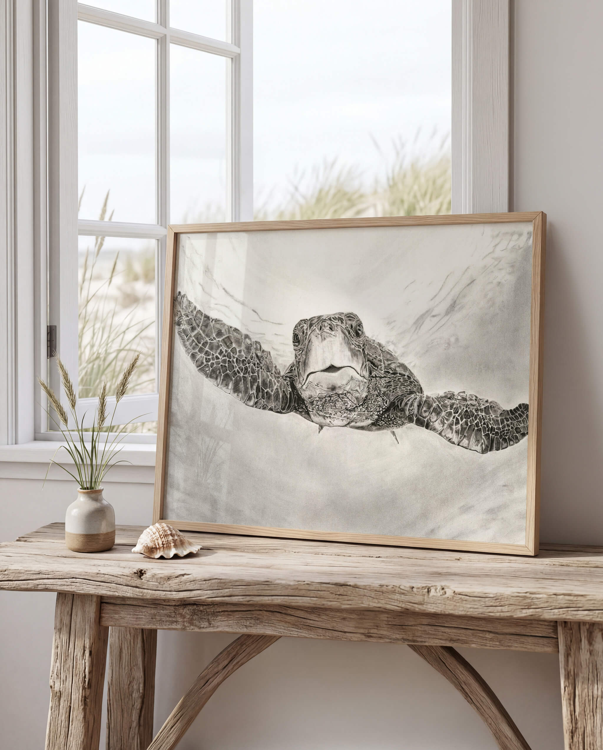 The Great Navigator sea turtle drawing art print on a driftwood console table by a beach dune window