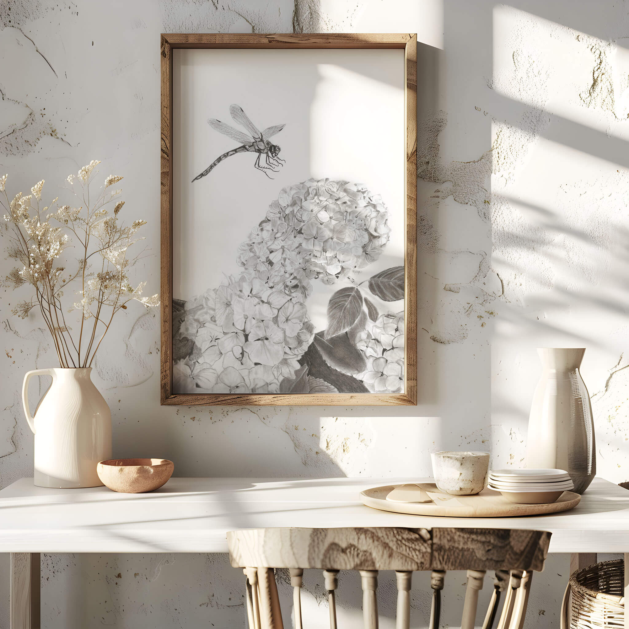 Touchdown dragonfly art print in an oak frame on a sunlit table with dried florals and ceramic pitchers
