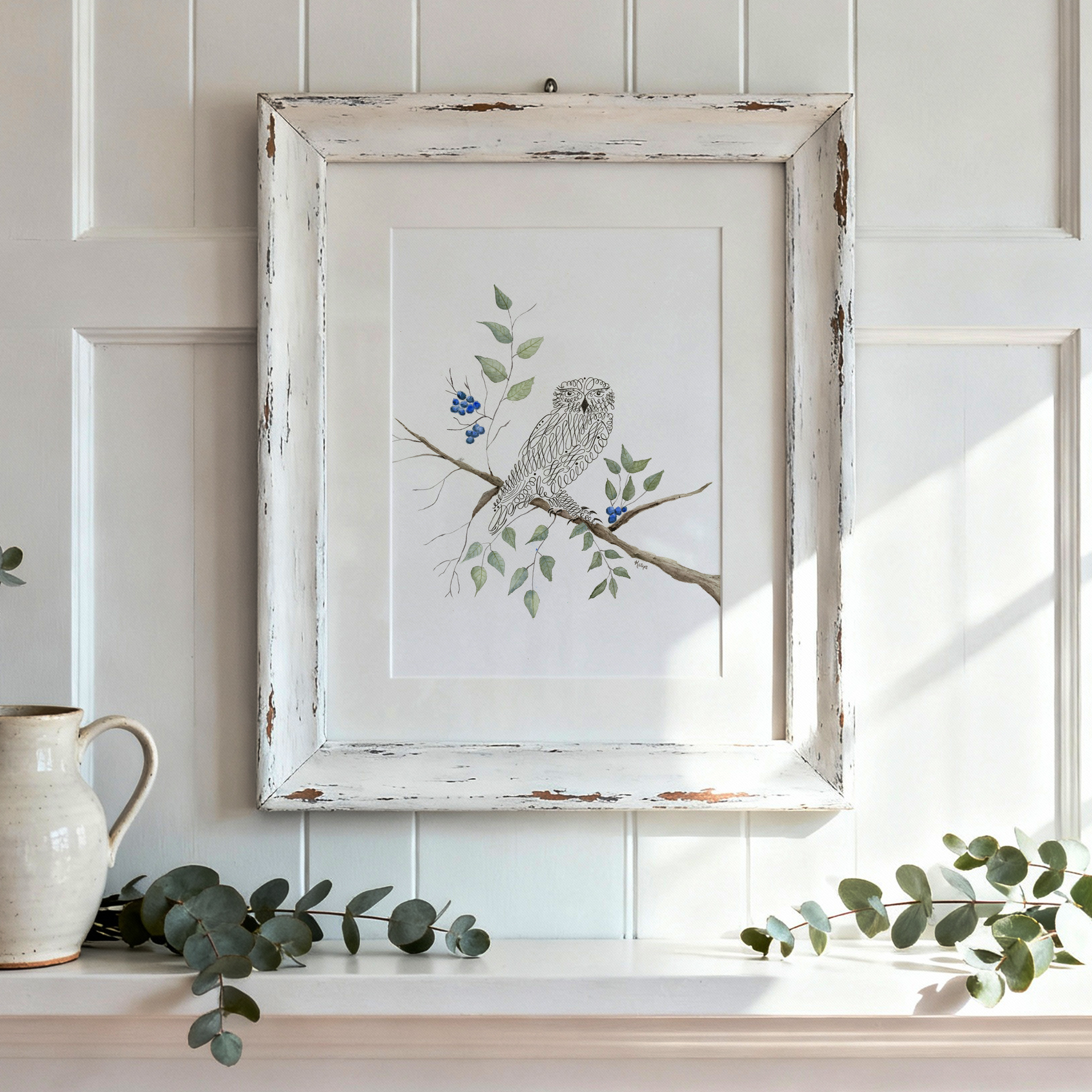 Hoot owl art print with calligraphy design in a distressed white frame on paneled wall, styled with a ceramic pitcher and eucalyptus branches