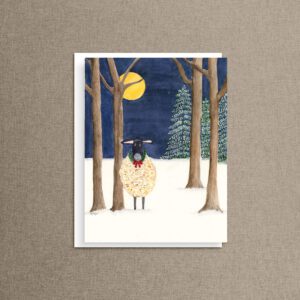 Fleece Navidad funny Christmas card showing a watercolor Suffolk sheep in a holly wreath, standing in snowy moonlit woods, on a white envelope
