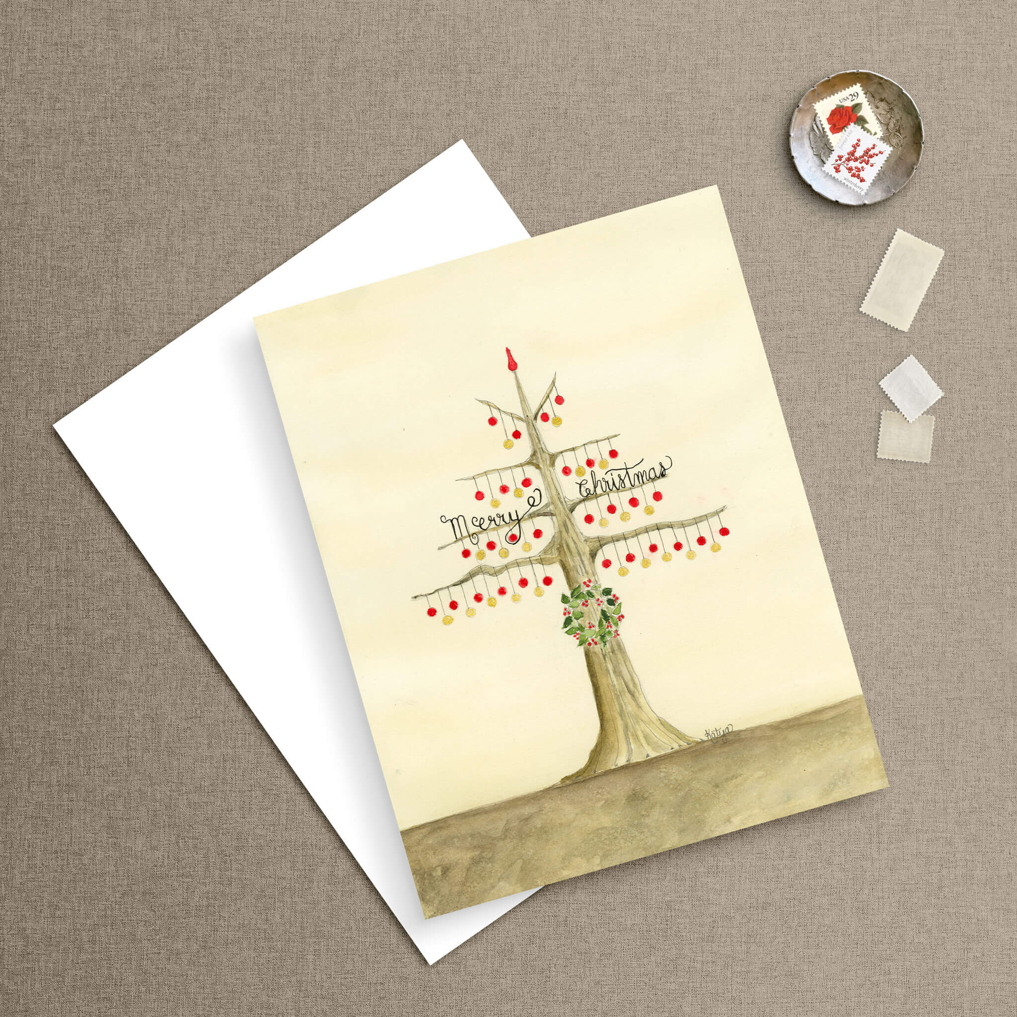 Christmas ornaments card featuring a hand-painted watercolor tree strung with red and gold baubles, paired with a crisp white envelope and vintage postage stamps.