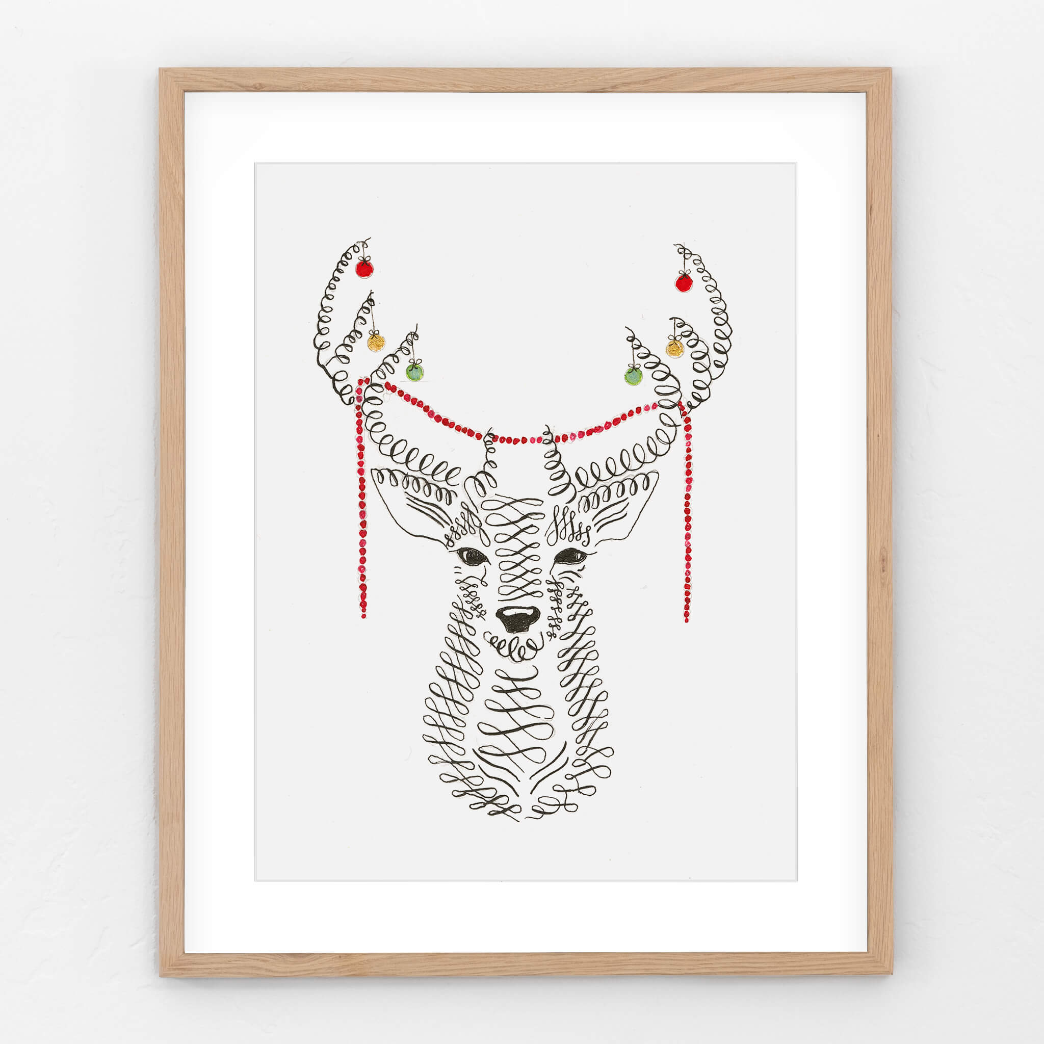 Original Christmas deer drawing in calligraphy ink, antlers hung with red, green and gold baubles and a red beaded garland, in a light oak frame.