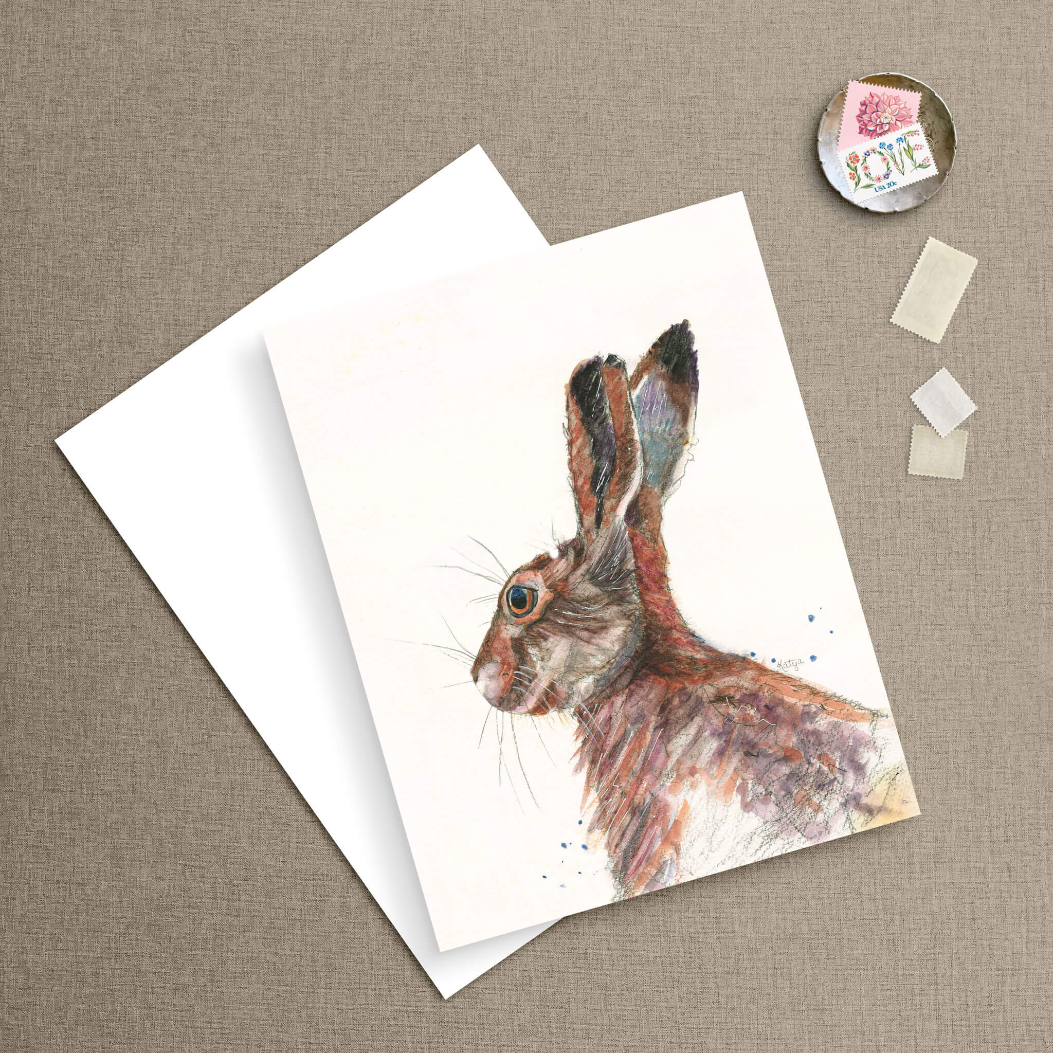 Watercolor rabbit note card and matching envelope styled on linen with vintage postage stamps — colorful rabbit art by Cathy Turner.