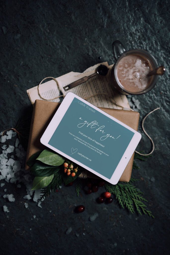 Cathy Turner digital gift card reading “a gift for you!” on a tablet, resting on a kraft-wrapped present beside hot cocoa and winter greenery, one of the best last minute Christmas gifts