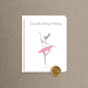 Inspirational greeting card with "Dance Like Nobody's Watching" script lettering above a twirling ballerina bunny in a pink polka-dot tutu, with a white envelope and gold wax seal on a taupe linen background